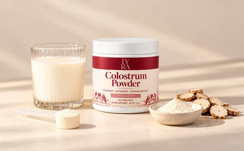 IYRA Colostrum Powder, a prepared drink, powder and dried root pieces on an ivory surface