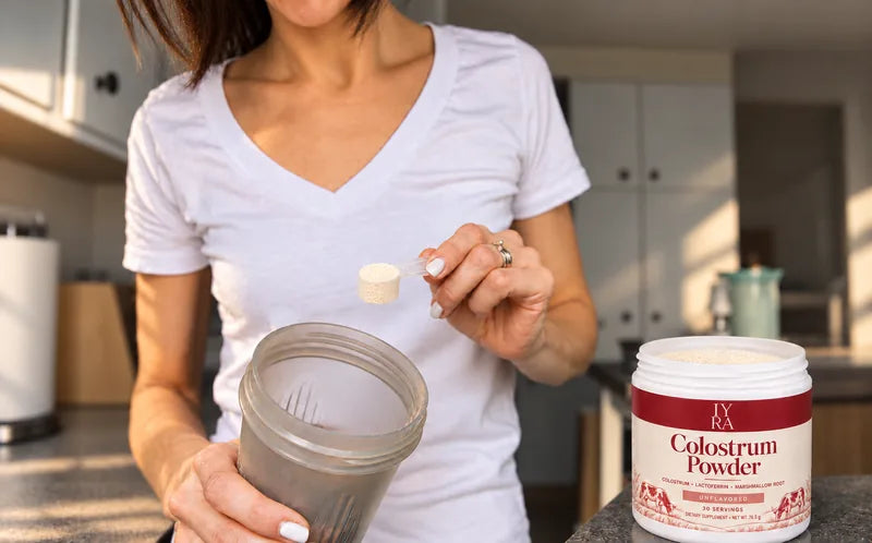 An included scoop beside IYRA Colostrum Powder